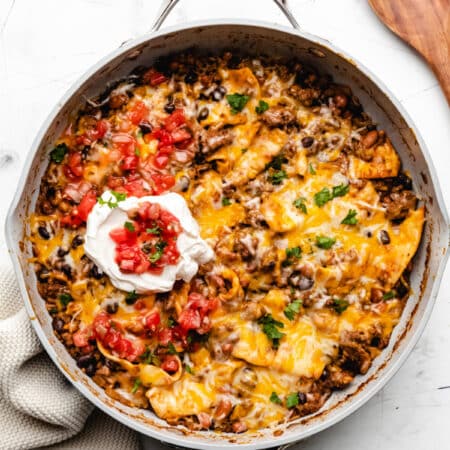 Ground beef burrito skillet next to a wooden spoon.