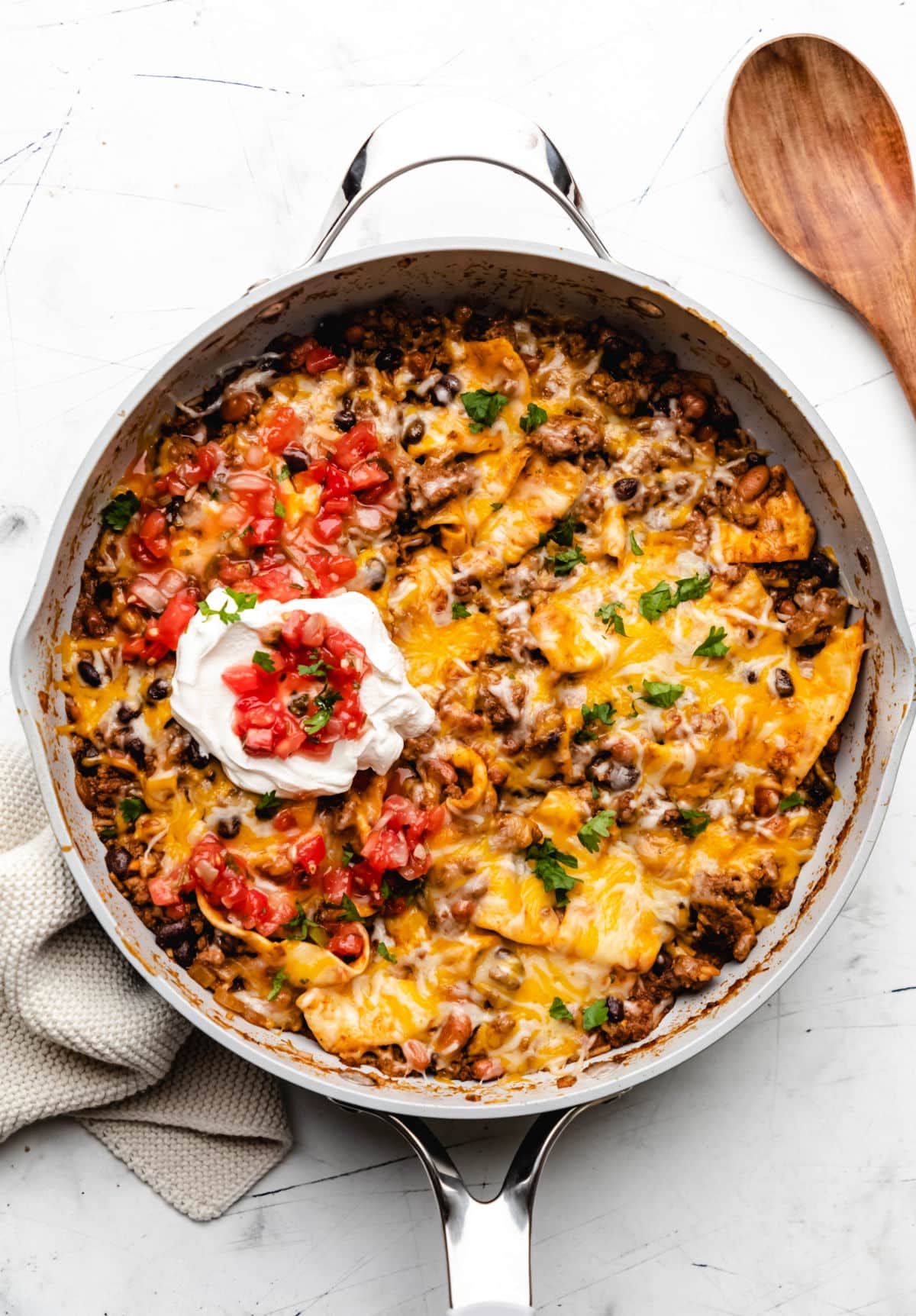 Ground beef burrito skillet next to a wooden spoon. 