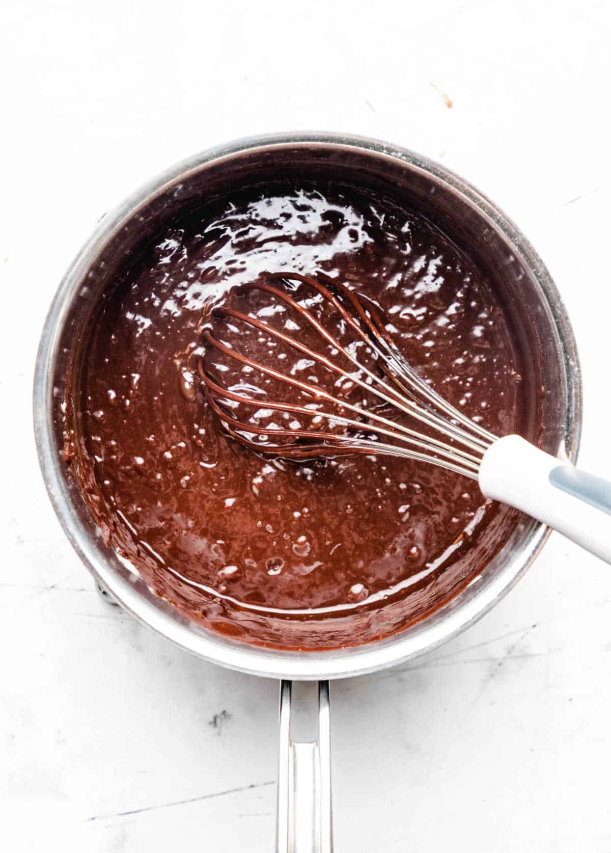 A whisk stirring eggs into melted chocolate mixture. 