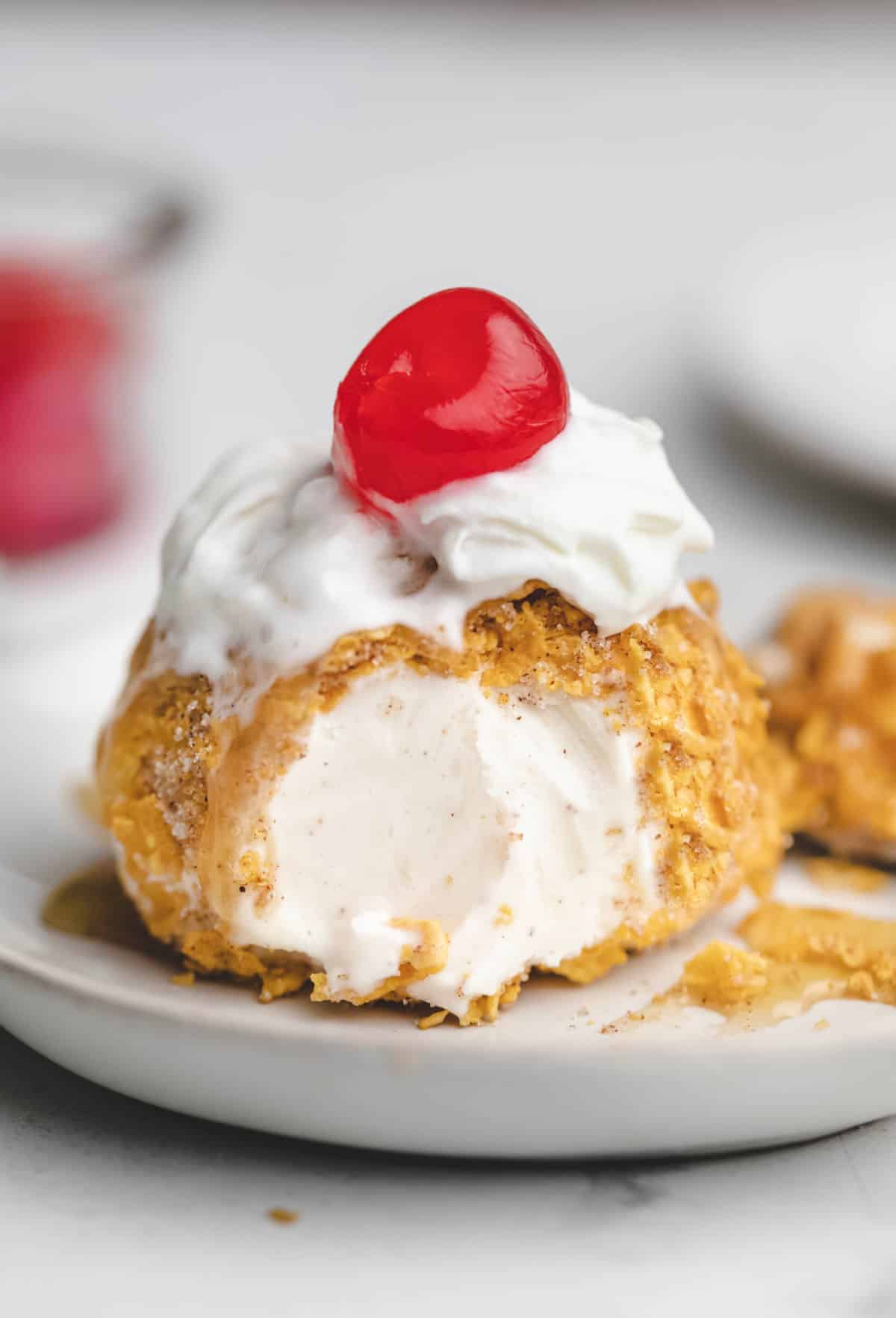 A scoop of no fry fried ice cream on a white plate.