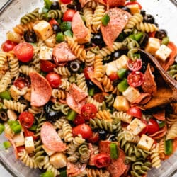 A glass mixing bowl full of pasta salad.