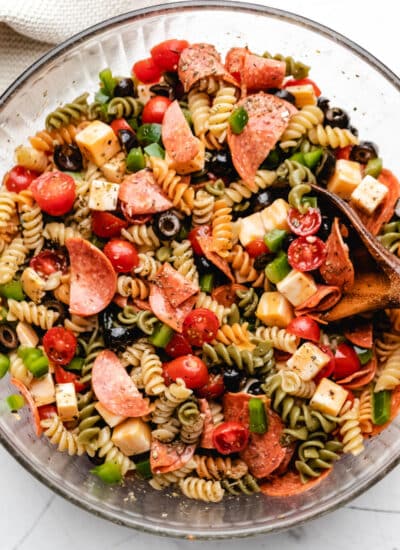 A glass mixing bowl full of pasta salad.