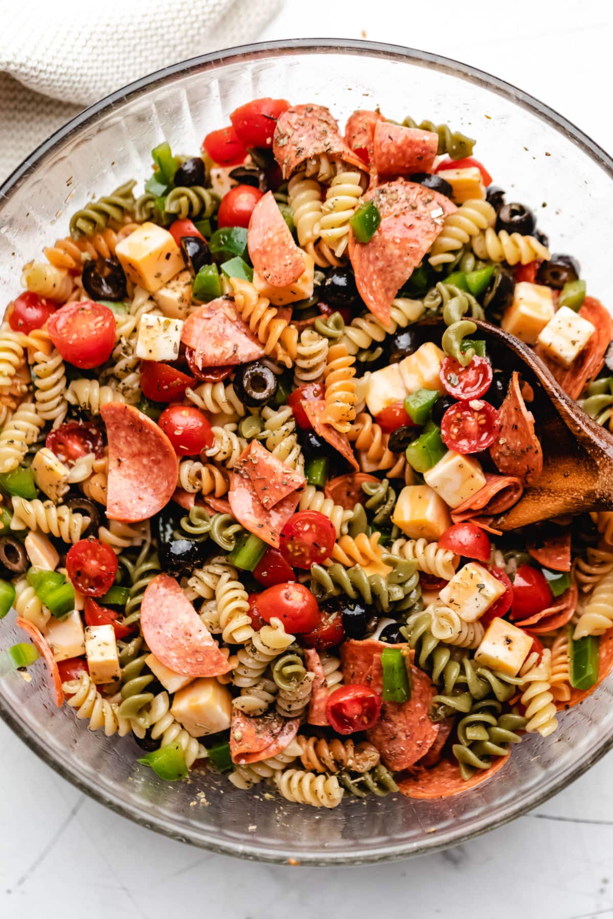 A glass mixing bowl full of pasta salad.