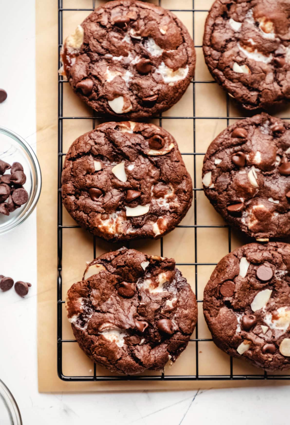 Rocky road cookies in rows next to a dish of chocolate chips. 