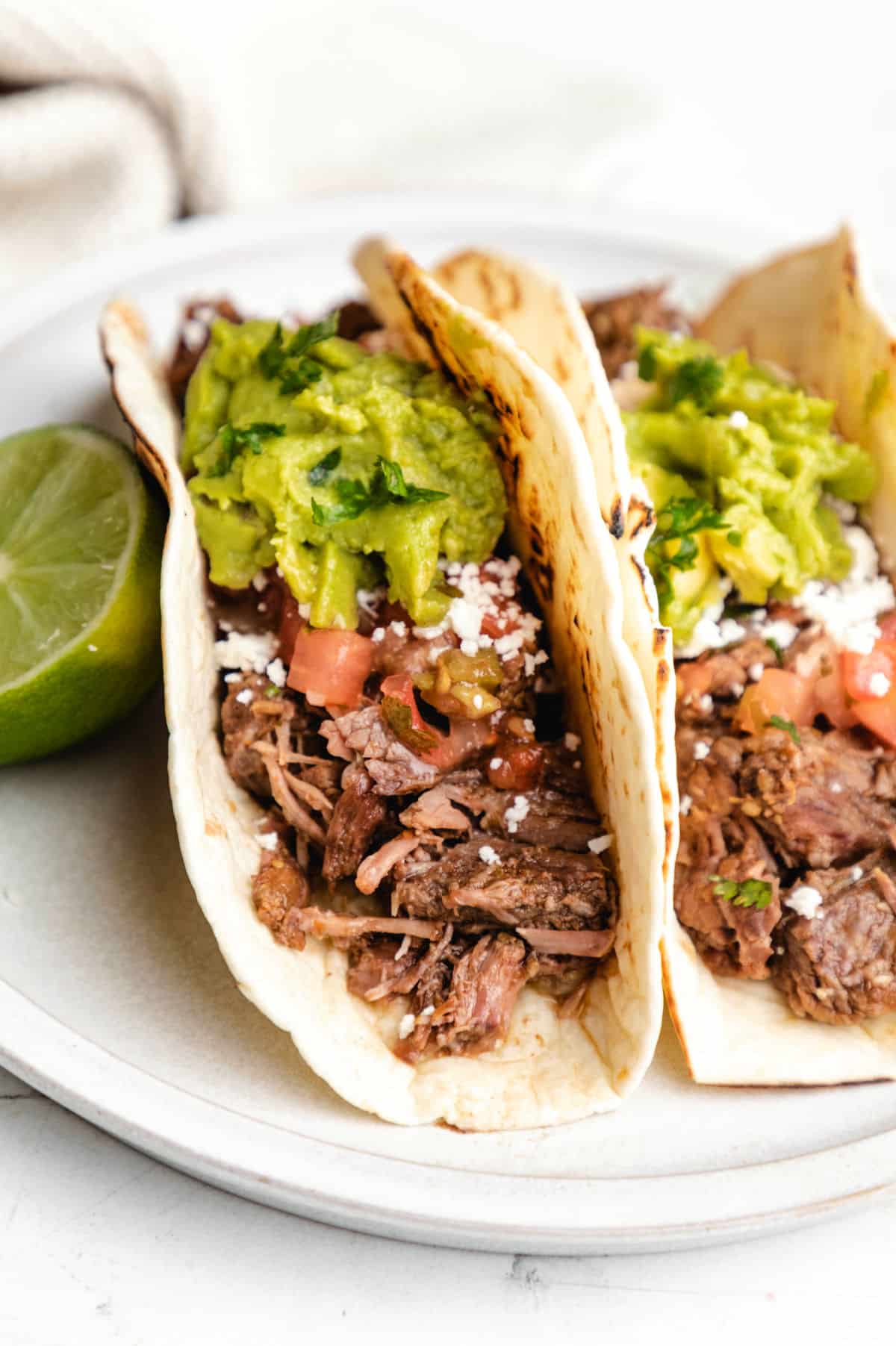 Two soft tacos filled with slow cooker salsa verde beef. 