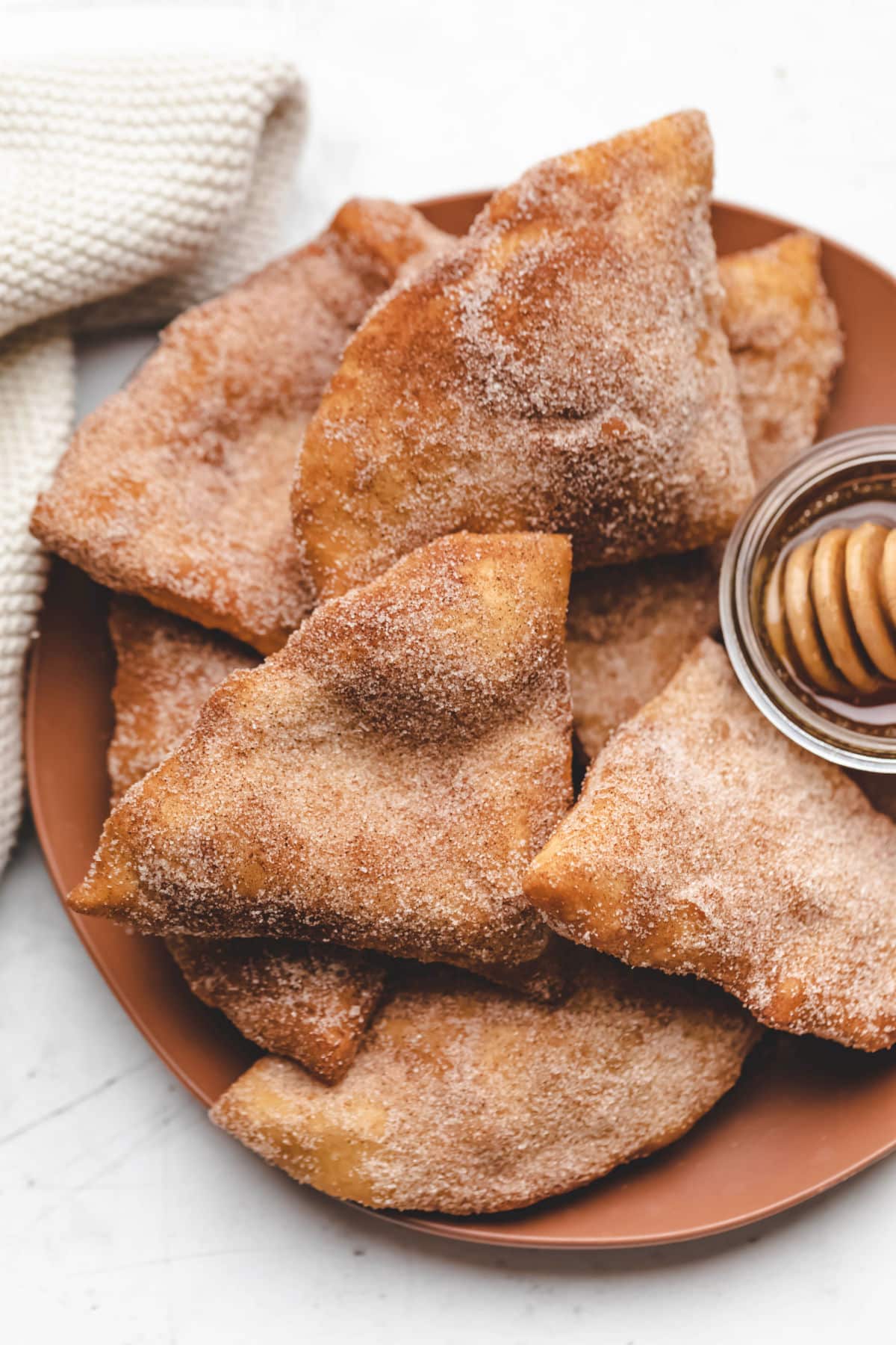Sopaipillas and a dish of honey on a plate. 