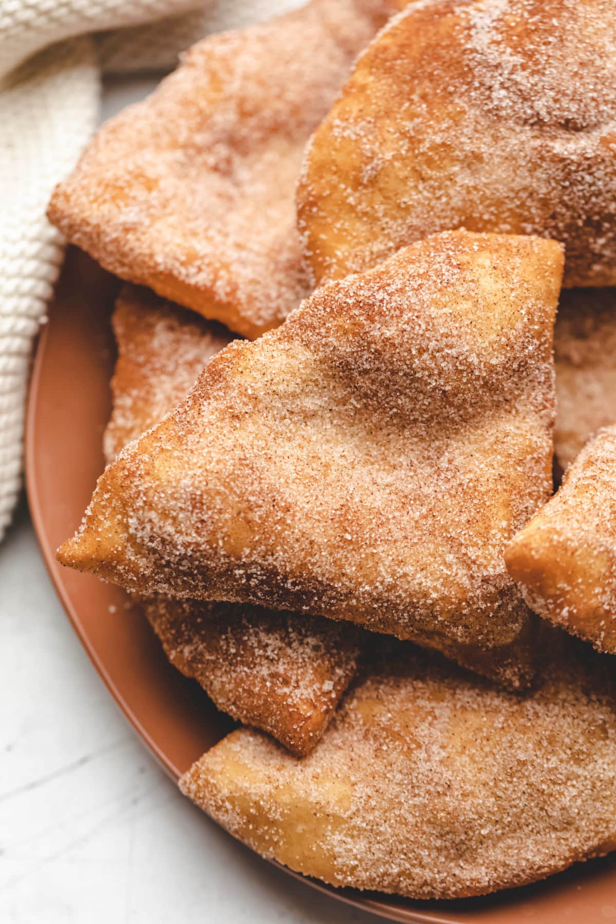 Close up photo of sopaipillas on a terra cotta colored dish. 