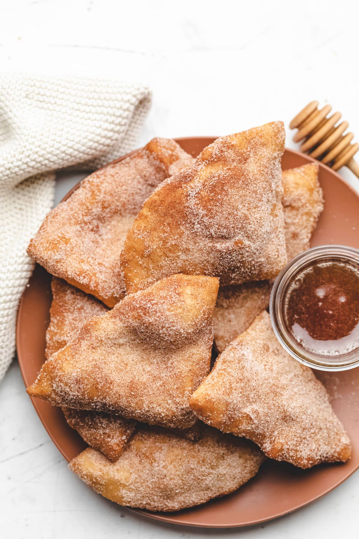 A plate of sopaipillas with a dish of honey on it. 