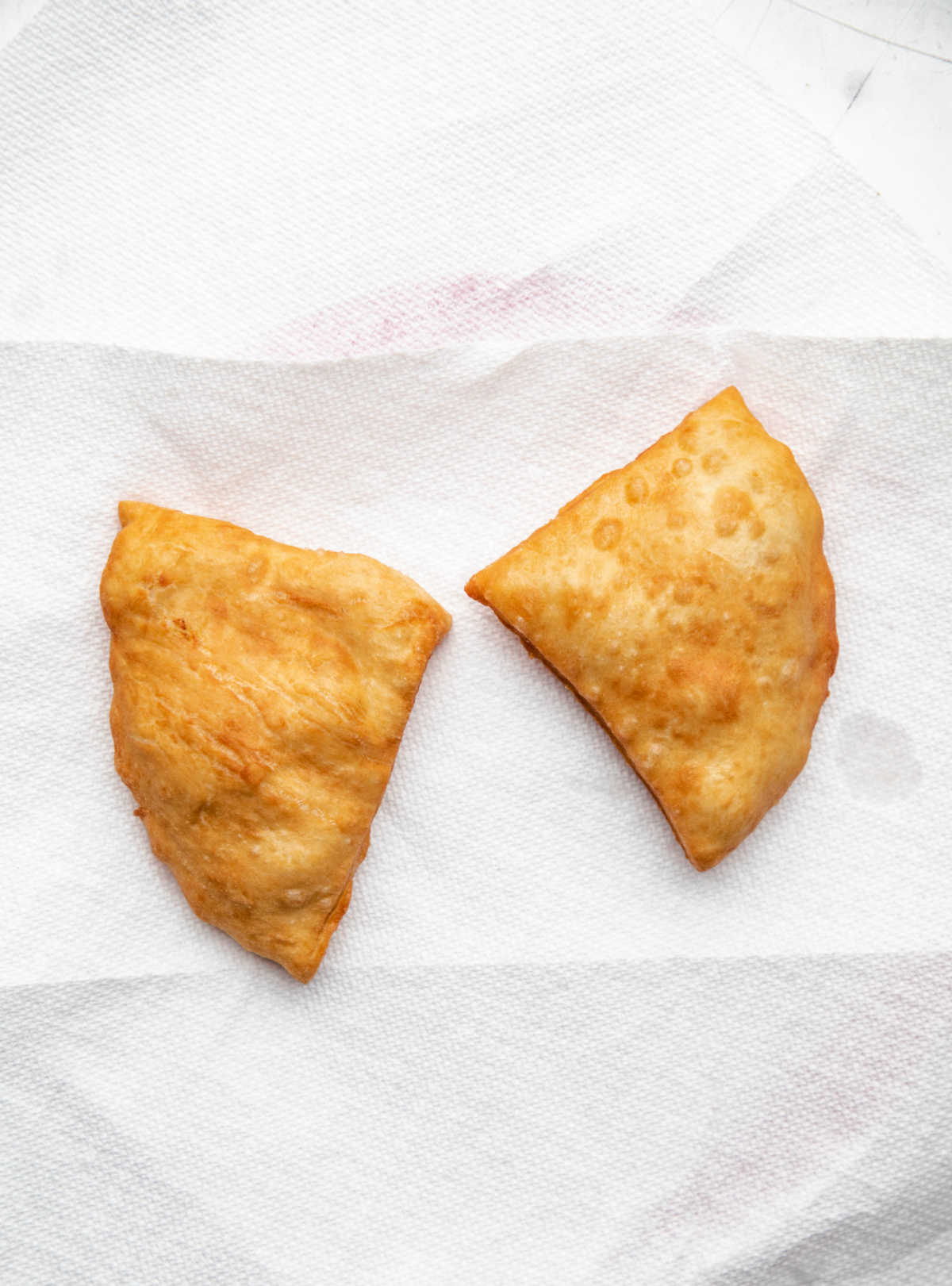 Two fried sopaipillas on paper towels. 