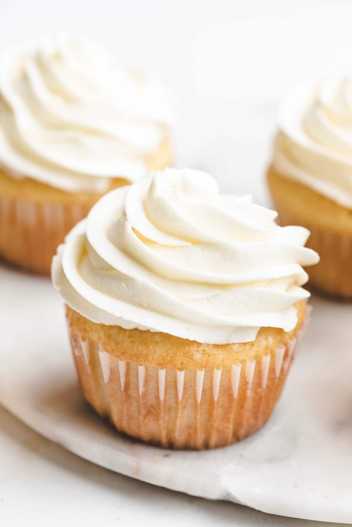 Vanilla cupcakes topped with swirled vanilla buttercream frosting. 
