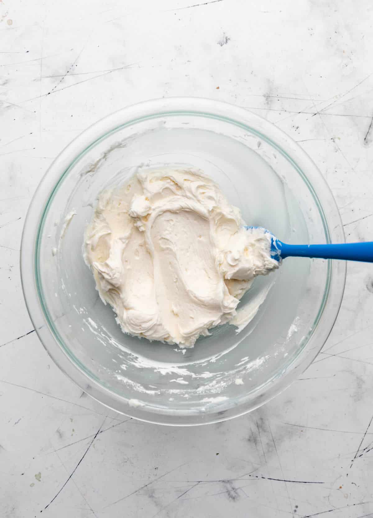 Powdered sugar beaten into butter in a glass mixing bowl. 