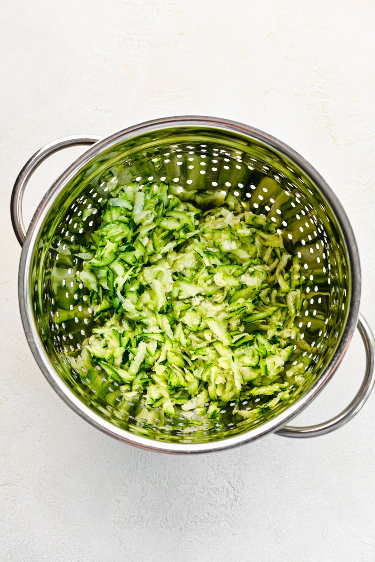 Grated zucchini in a metal colander. 