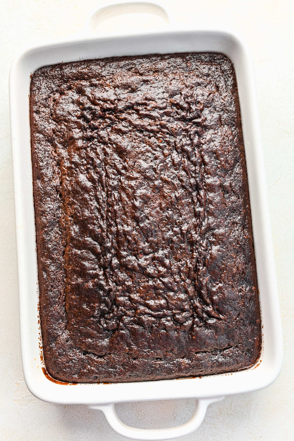 Baked chocolate zucchini cake in a white baking pan.