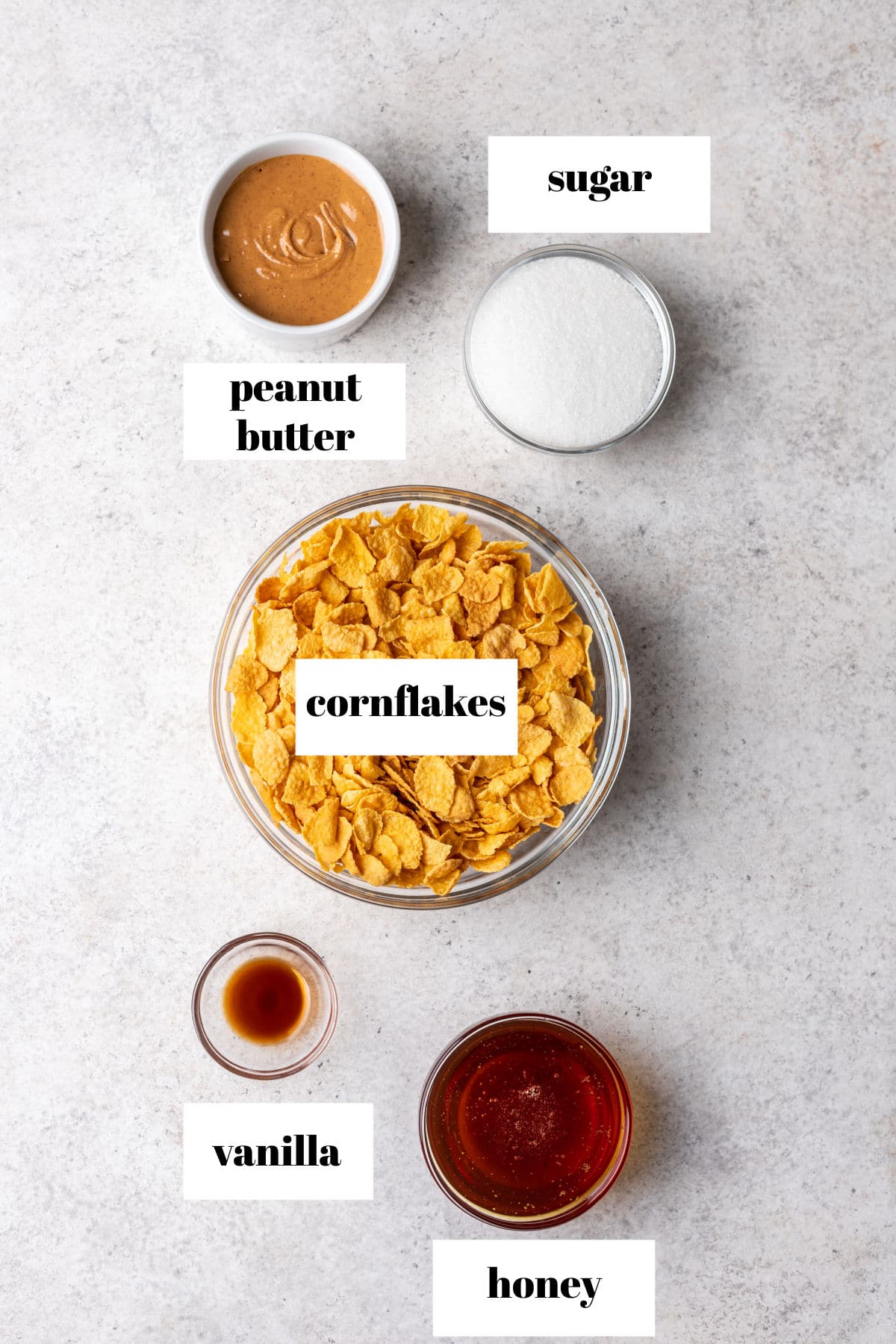 Labeled photo of ingredients for peanut butter cornflake cookies in dishes. 