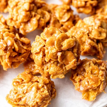 A white plate with several peanut butter cornflake cookies on it.