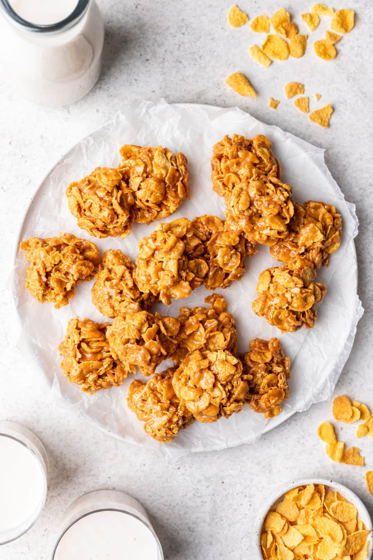 A white plate filled with peanut butter cornflake cookies next to a glass of milk.