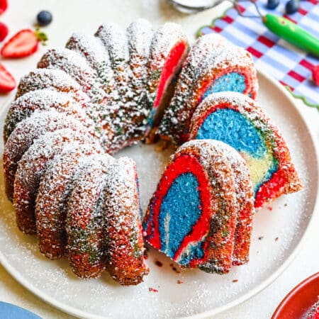 A red white and blue bundt cake with three slices cut from it.