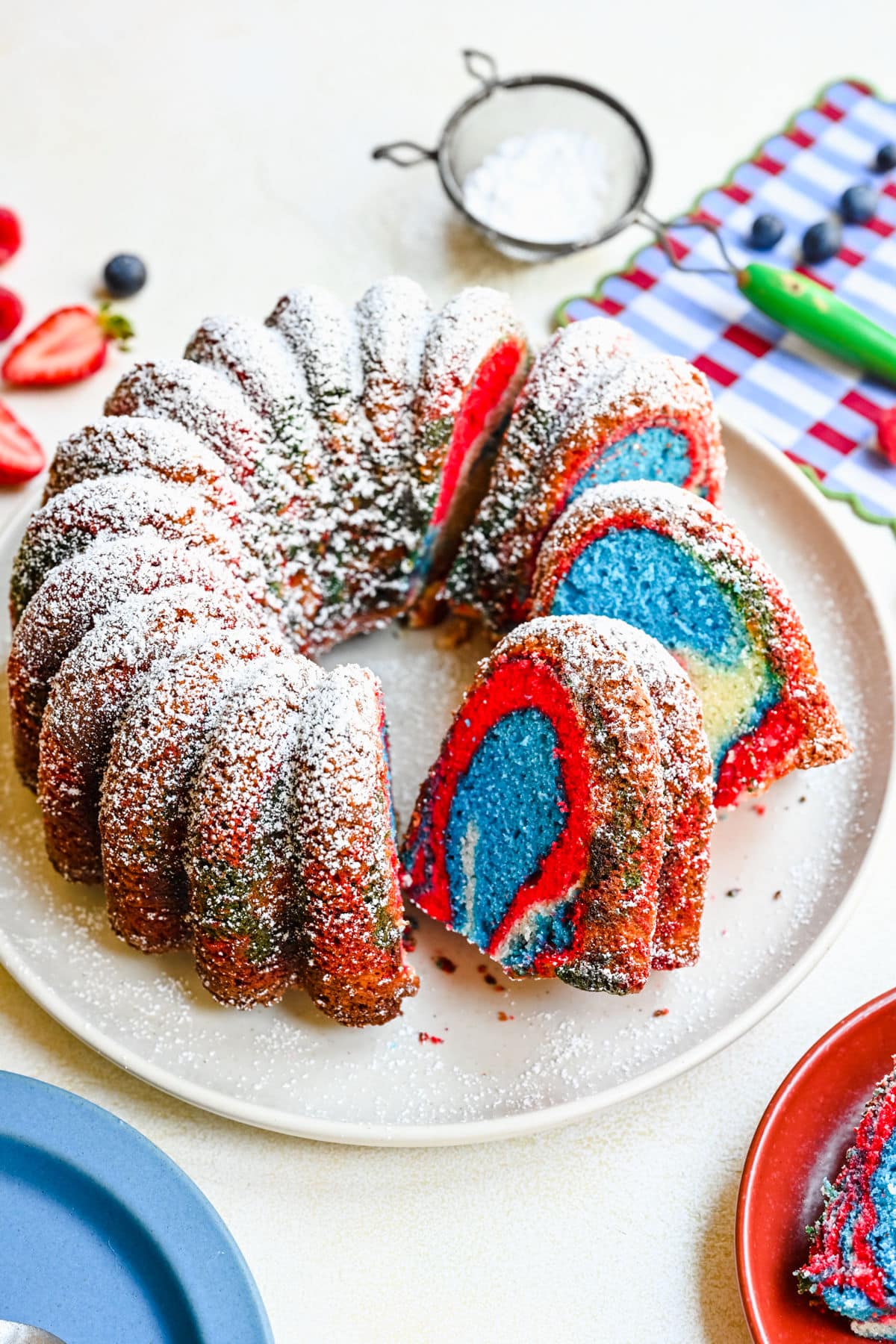 A red white and blue bundt cake with three slices cut from it.