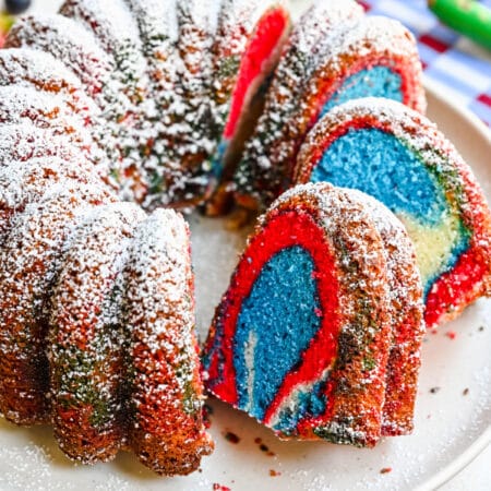 A red white and blue bundt cake with slices cut and faced forward.