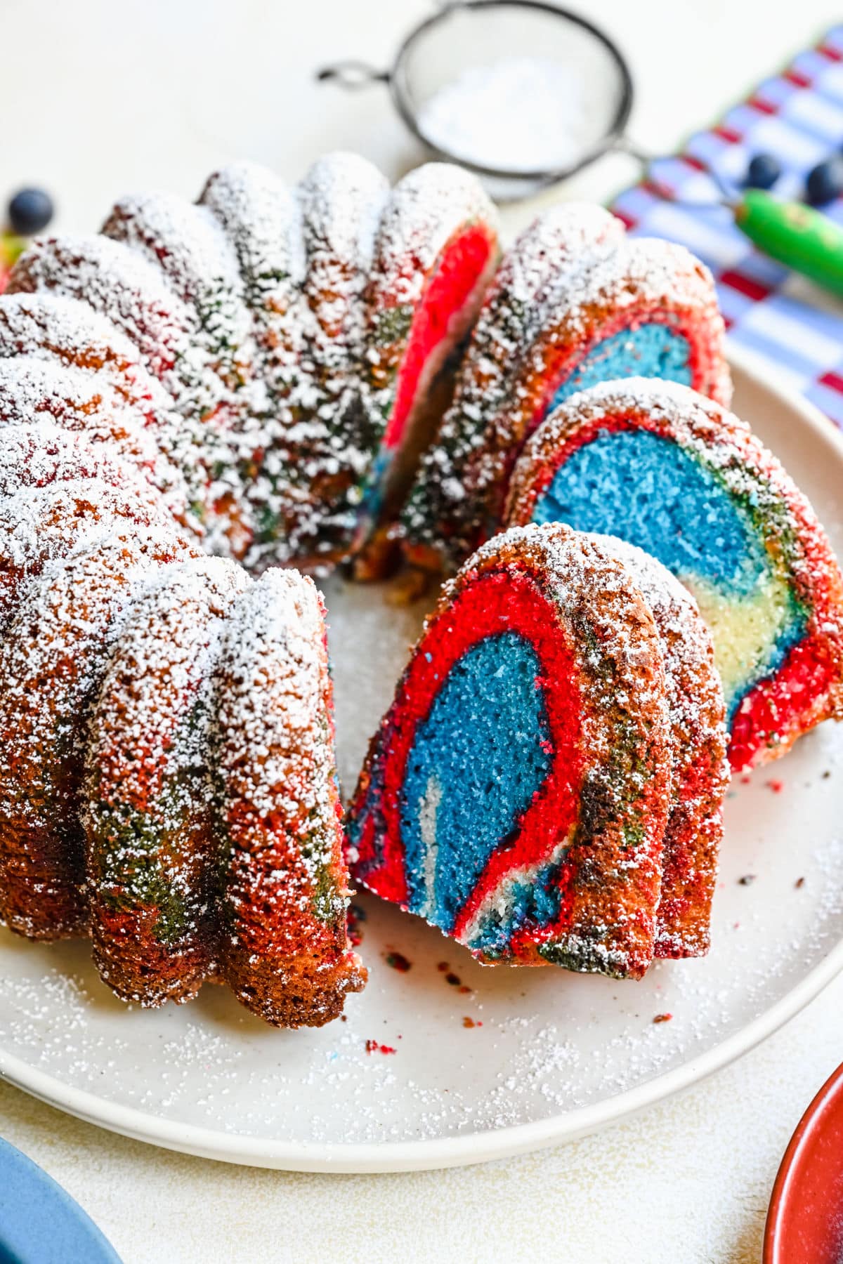 A red white and blue bundt cake with slices cut and faced forward. 