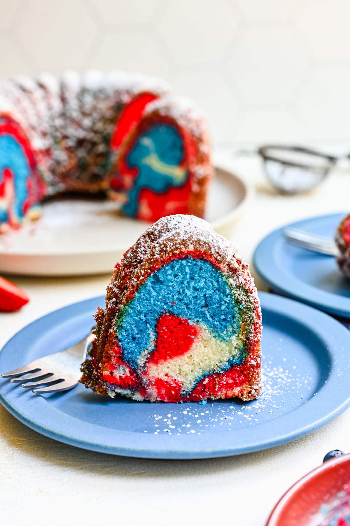 An upright slice of red white and blue bundt cake on a blue place.