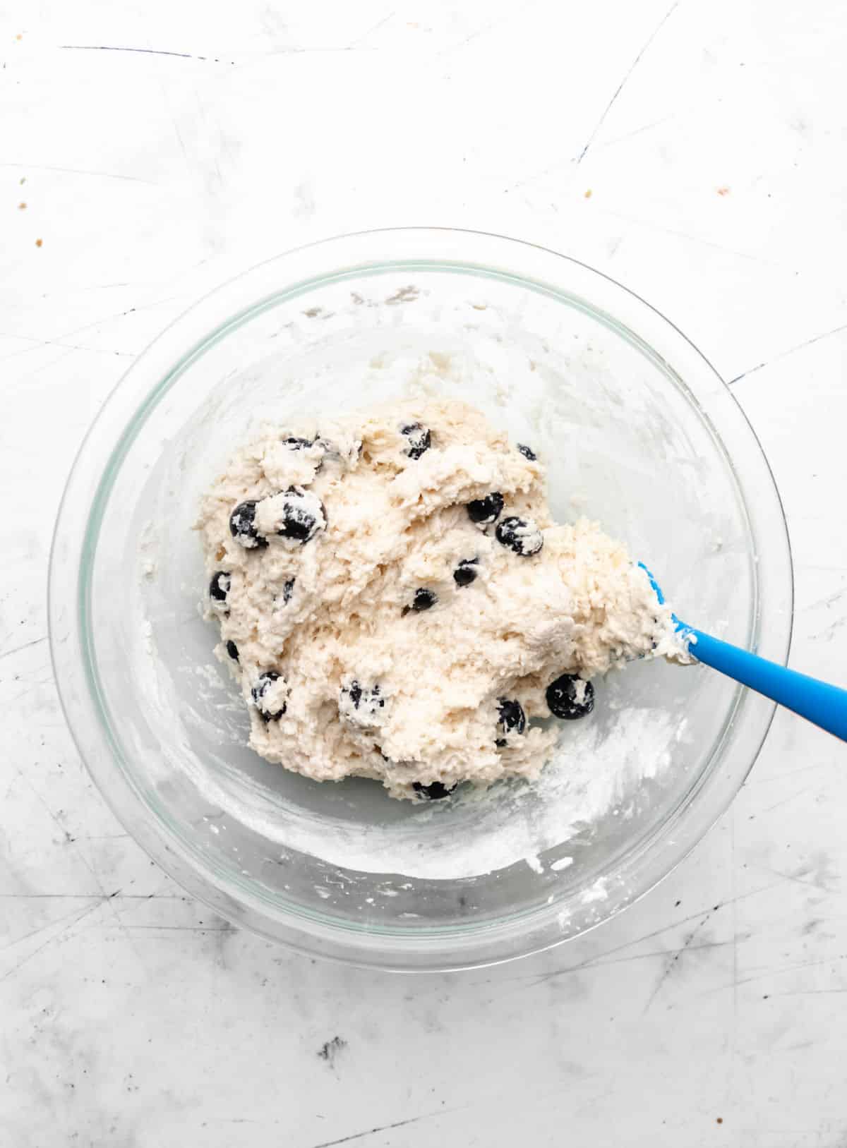 Blueberry biscuit dough in a glass mixing bowl. 