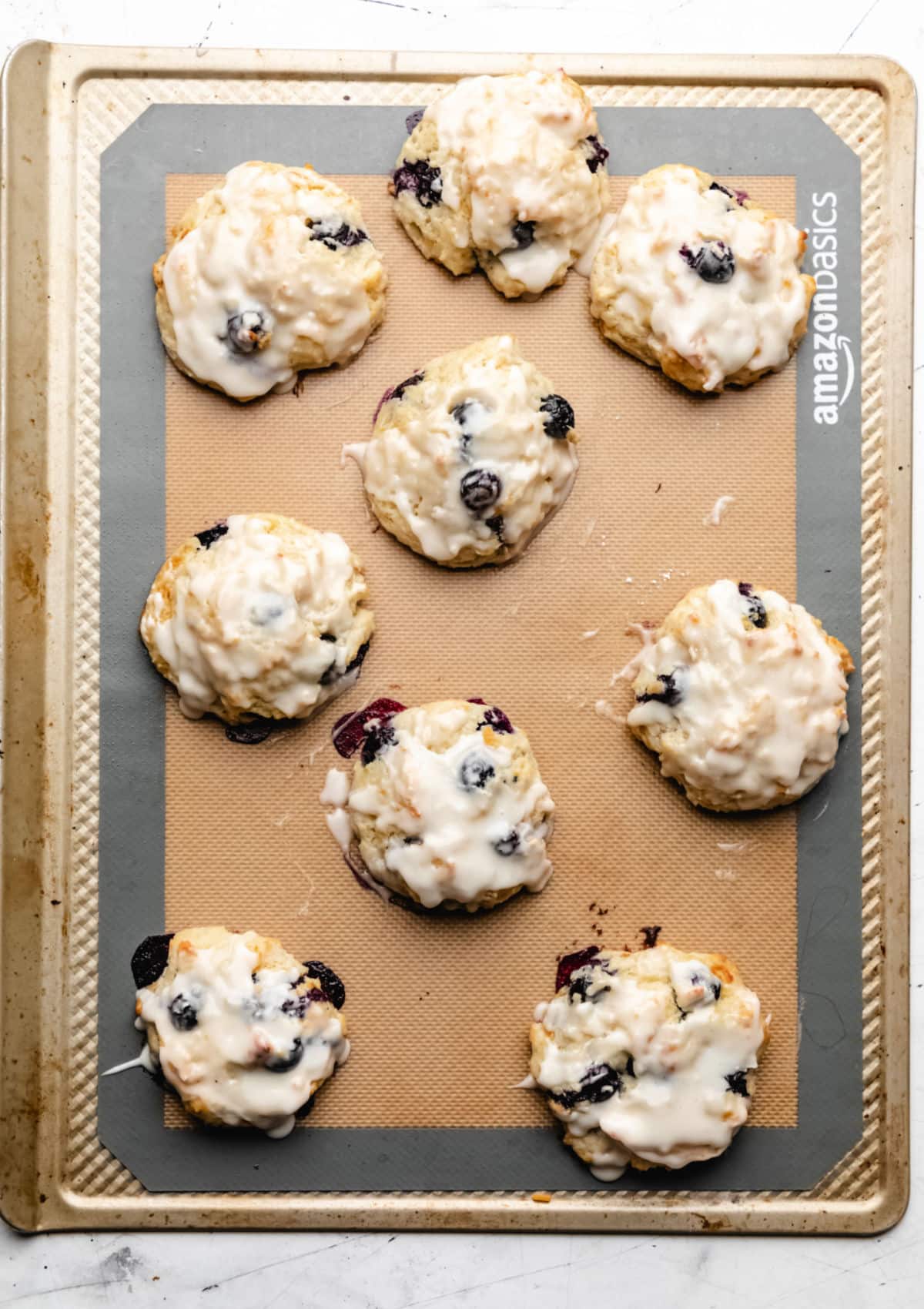 Glazed blueberry biscuits on a baking sheet. 
