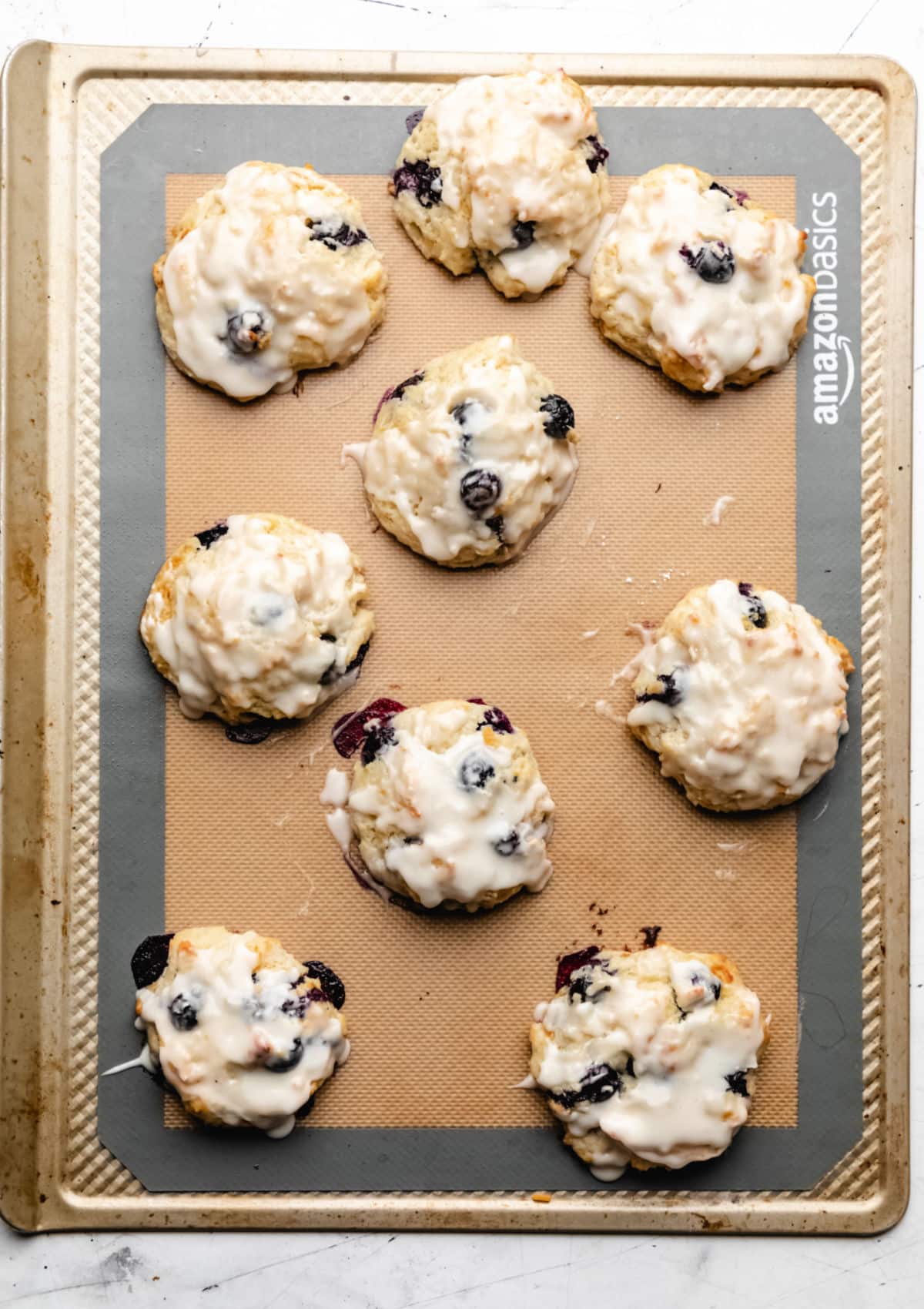 Glazed blueberry biscuits on a baking sheet.