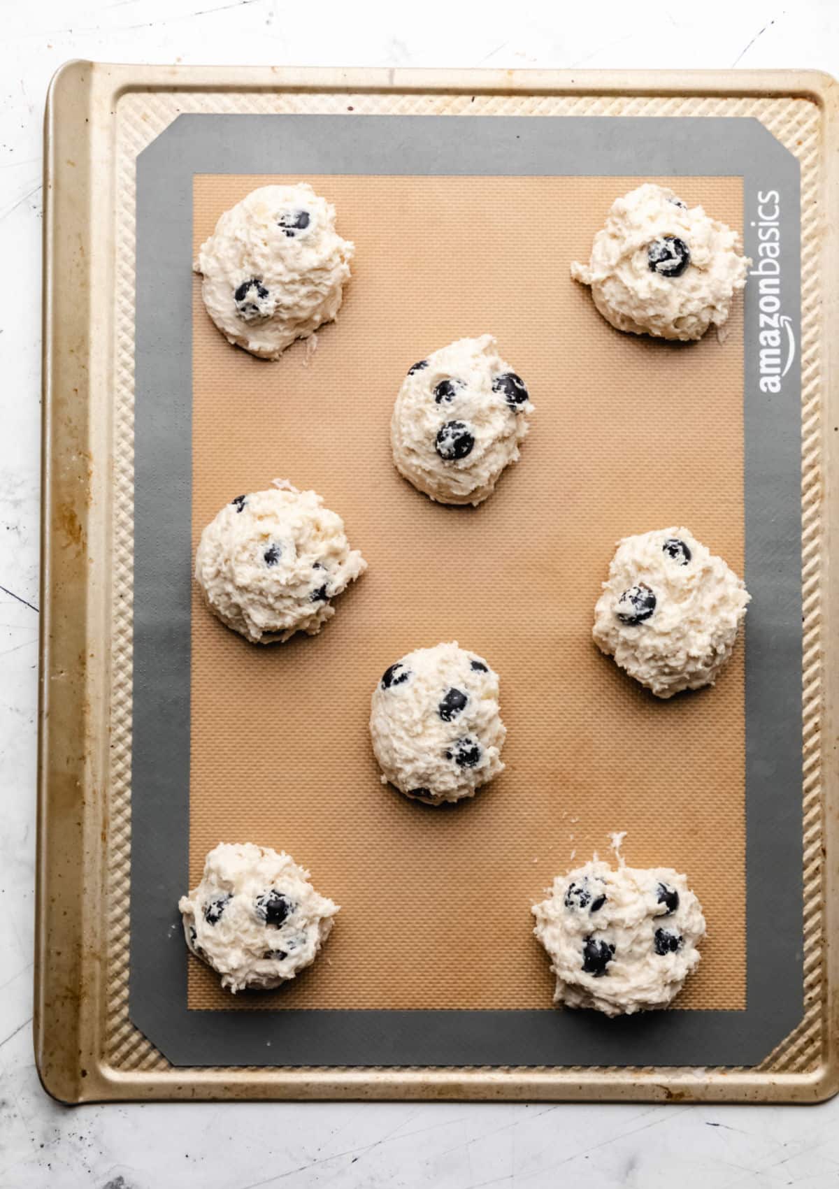Unbaked blueberry biscuits on a baking sheet. 