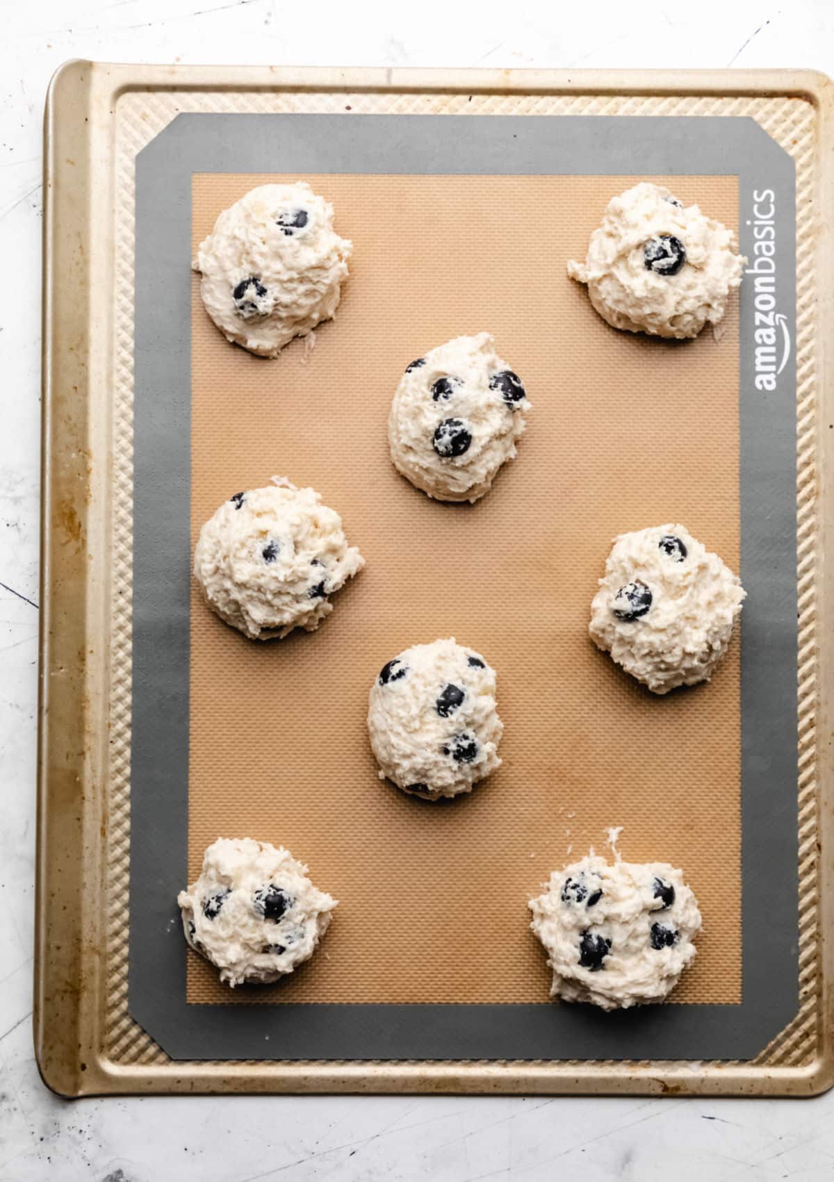 Unbaked blueberry biscuits on a baking sheet.