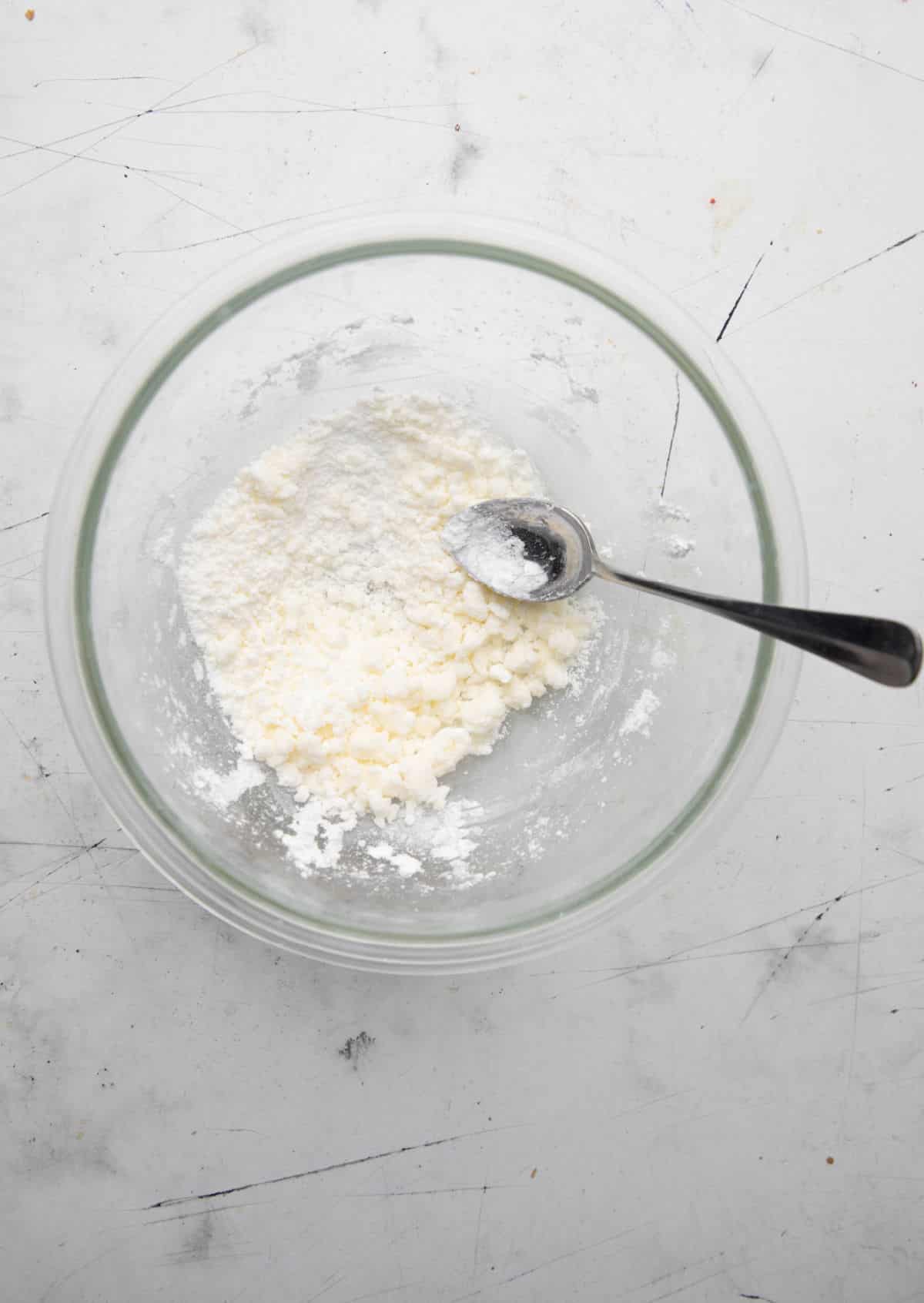 Butter and powdered sugar in a glass mixing bowl.