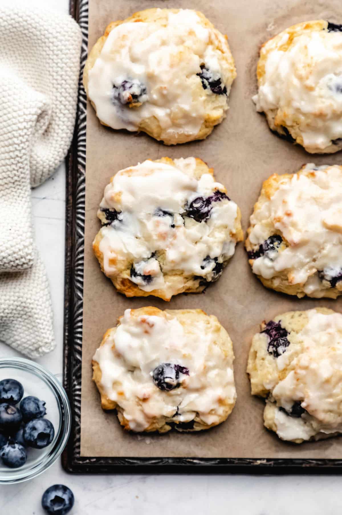 Overhead photo of rows of blueberry biscuits next to a dish of blueberries. 