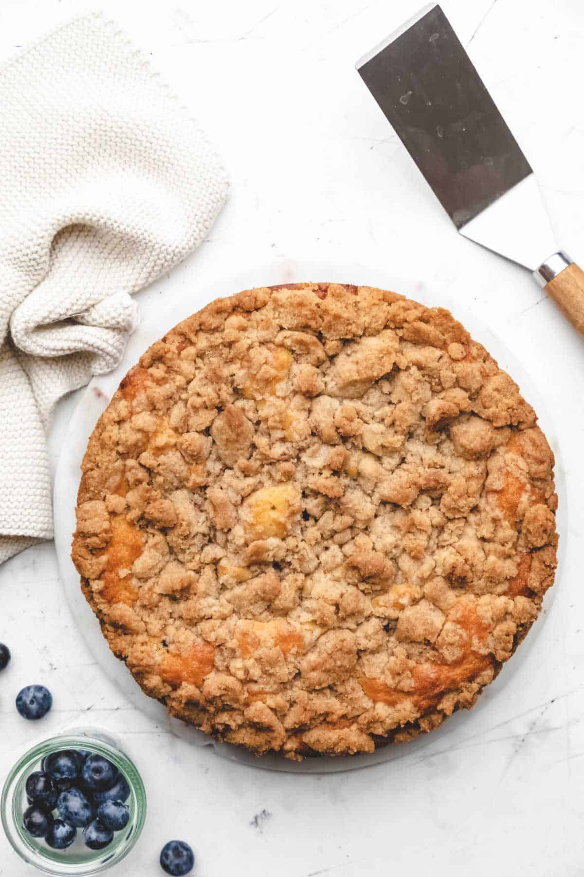 A baked blueberry coffee cake next to a dish of blueberries. 