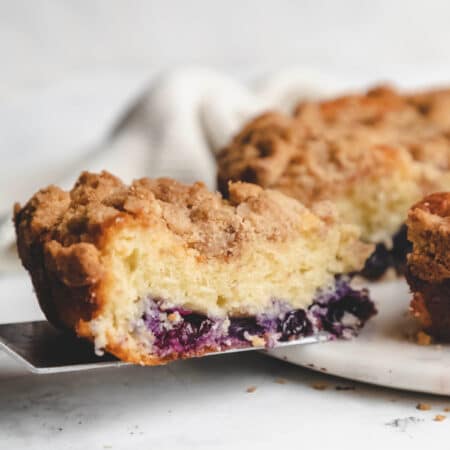 A slice of blueberry coffee cake on a cake server.