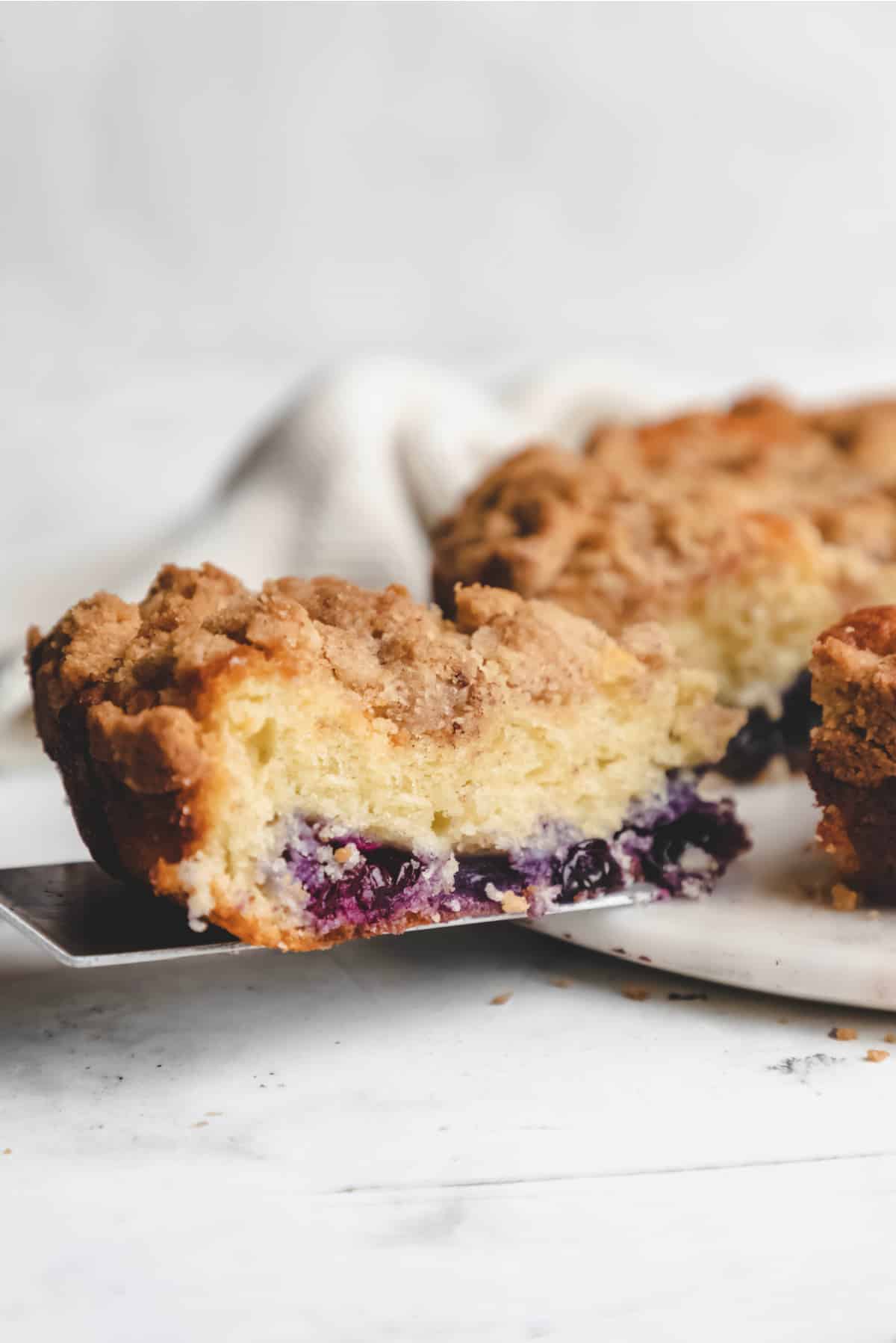 A slice of blueberry coffee cake on a cake server.