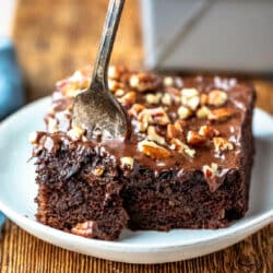 A fork taking a bite of chocolate zucchini cake on a plate.