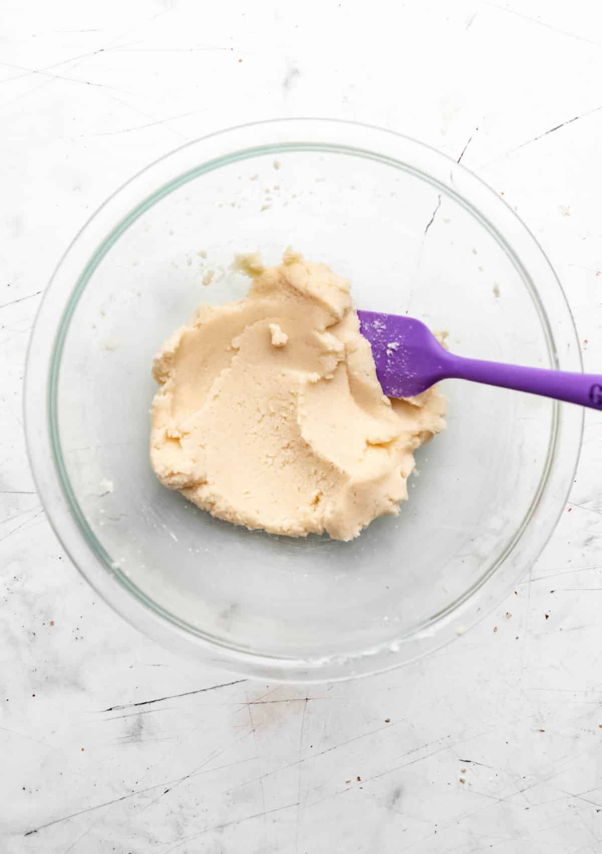 Creamed butter and sugar mixture in a glass mixing bowl.