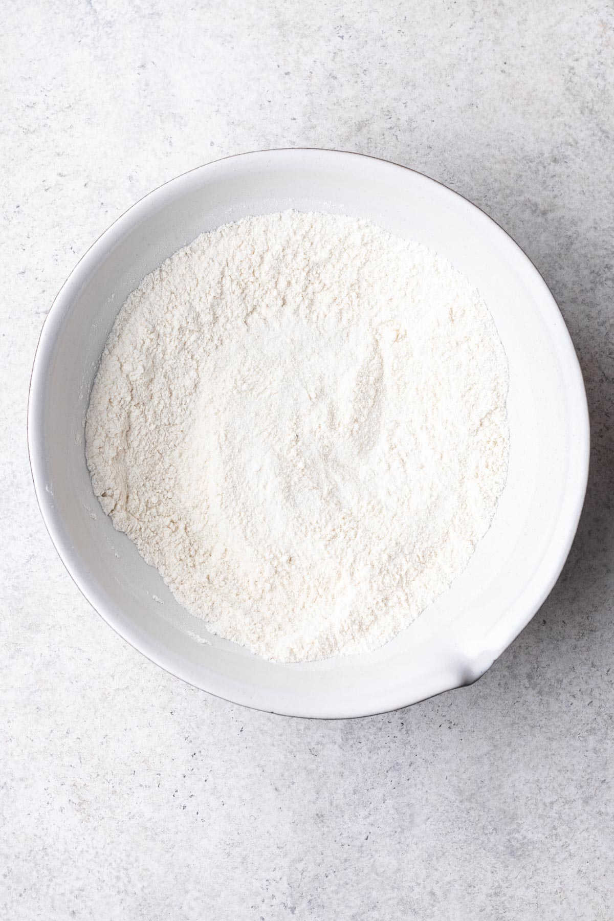 A bowl filled with dry ingredients for mini blueberry muffins.