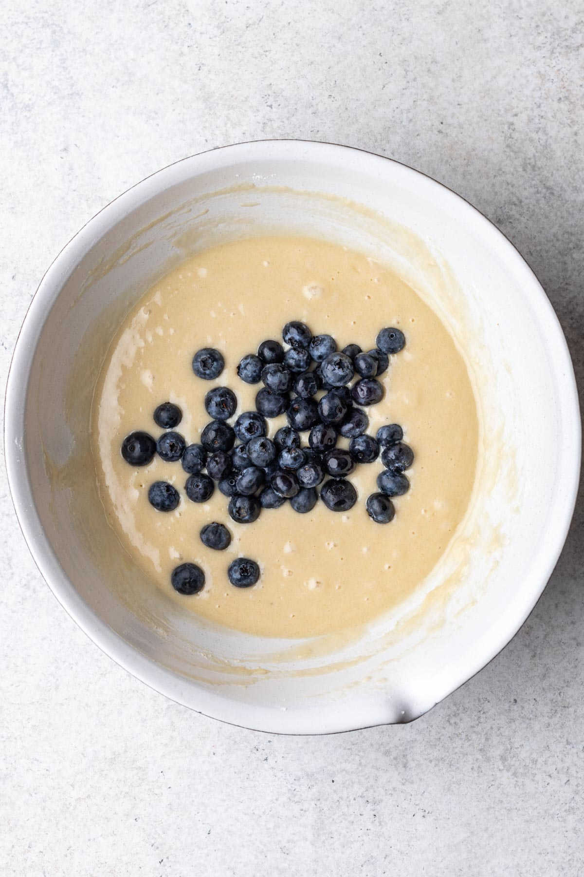 Blueberry muffin batter topped with fresh blueberries.