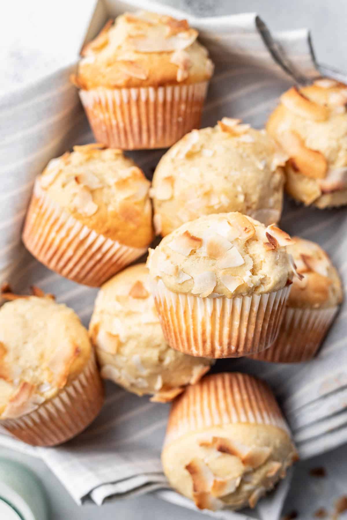 One coconut muffin on top of other coconut muffins.