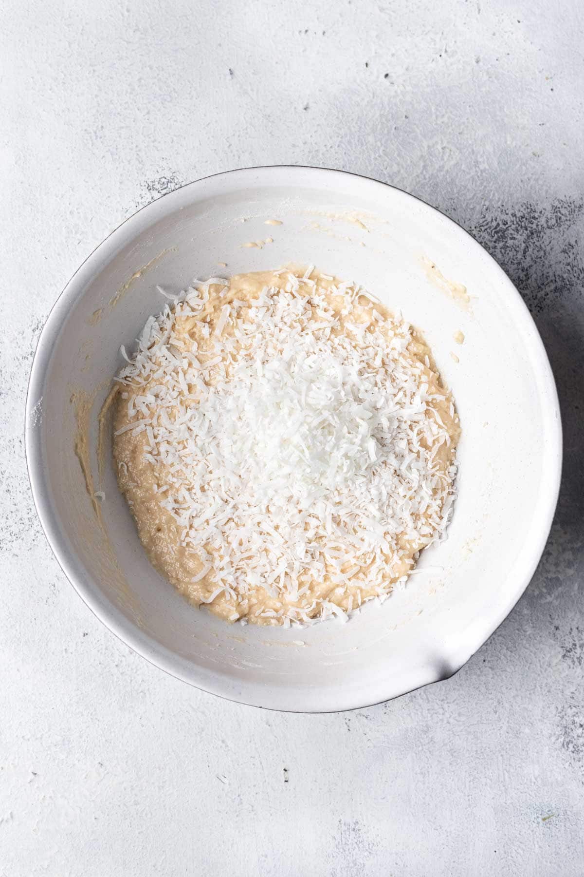 Shredded coconut on top of coconut muffin batter.