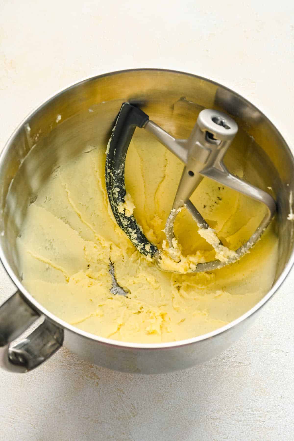 Creamed butter and sugar mixture in a silver mixing bowl. 