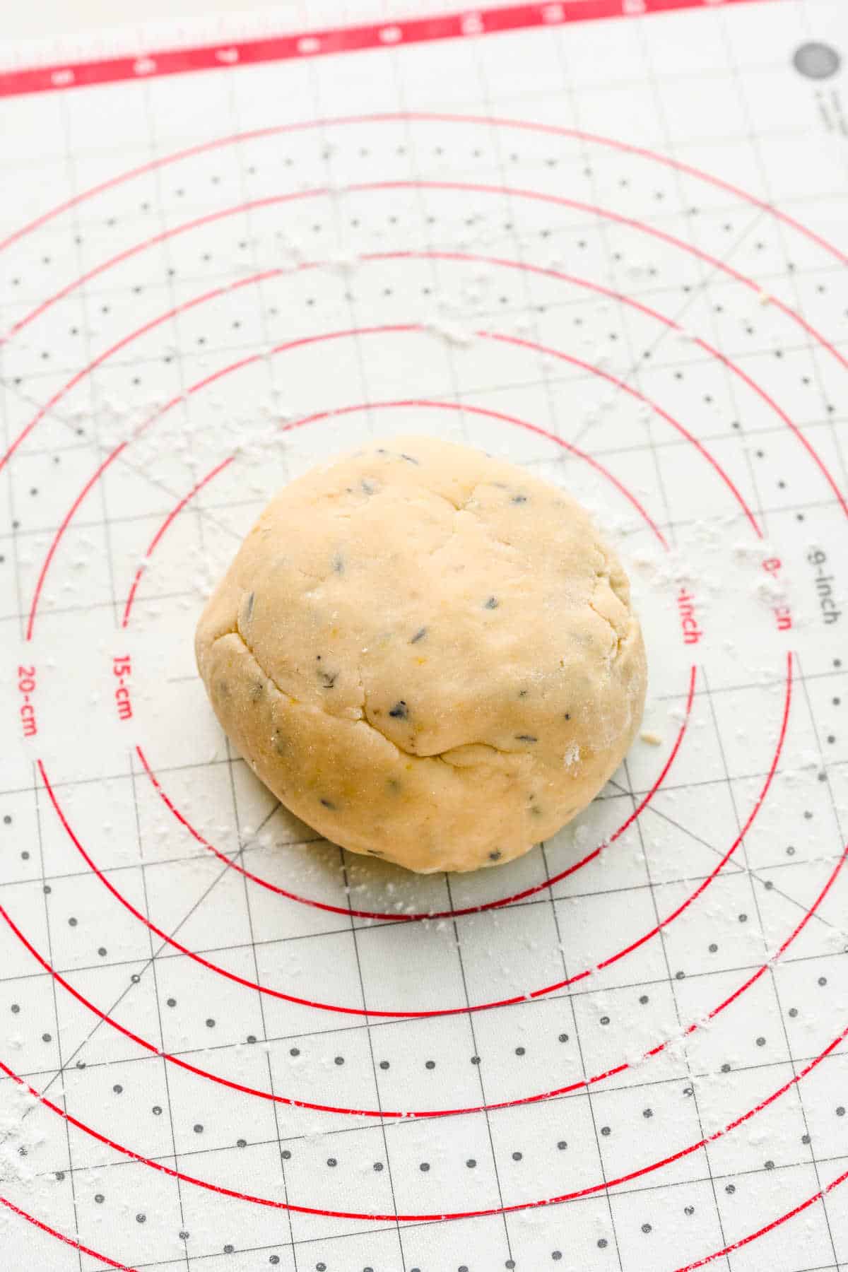 A ball of lavender cookie dough on a baking mat.