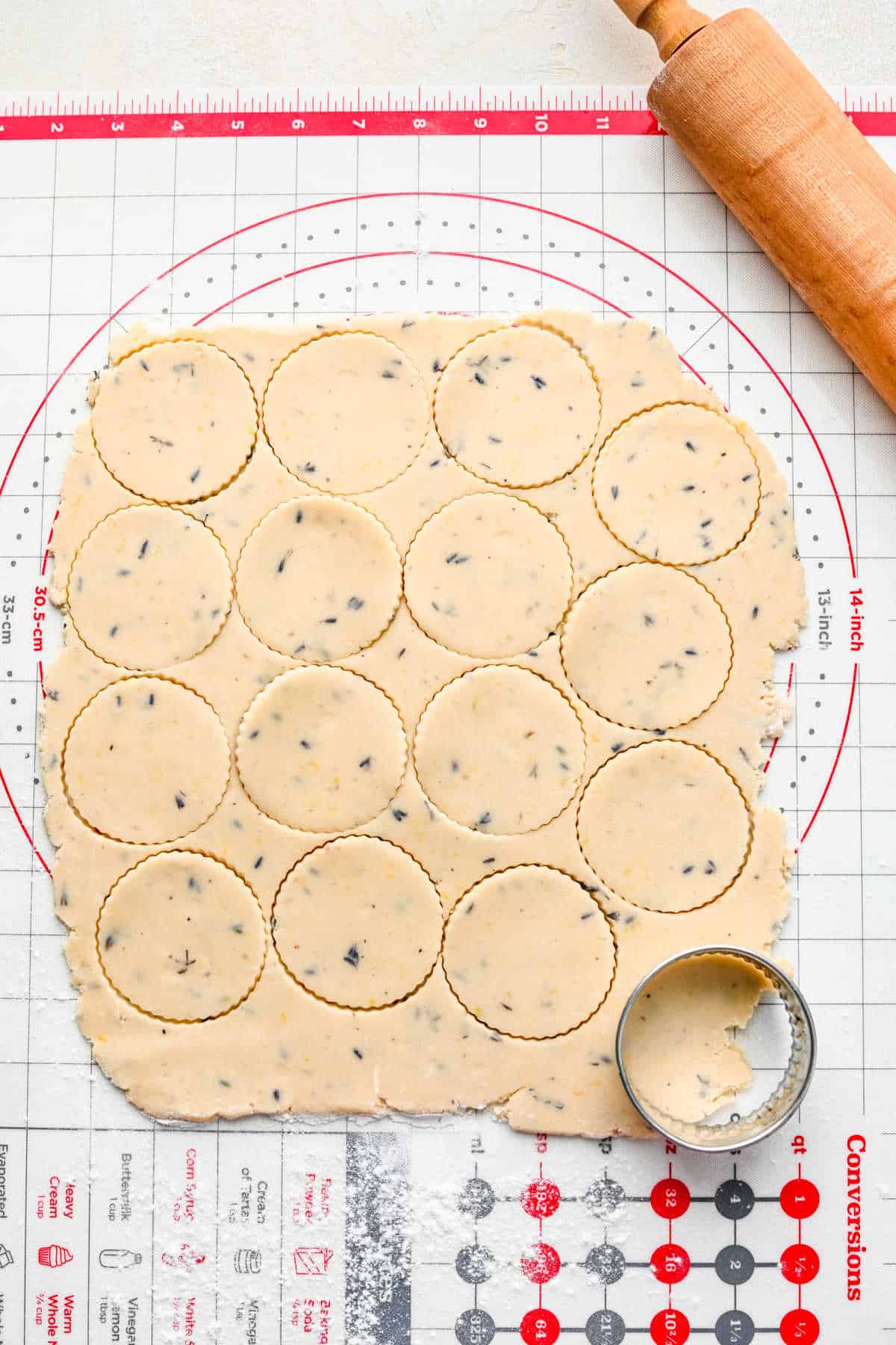 Cut lavender cookie dough next to a rolling pin.