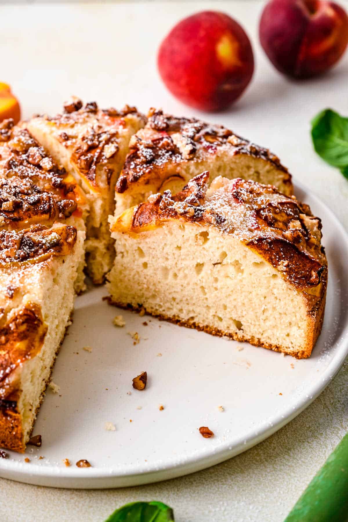 A slice of peach cake cut from the cake on a white plate. 