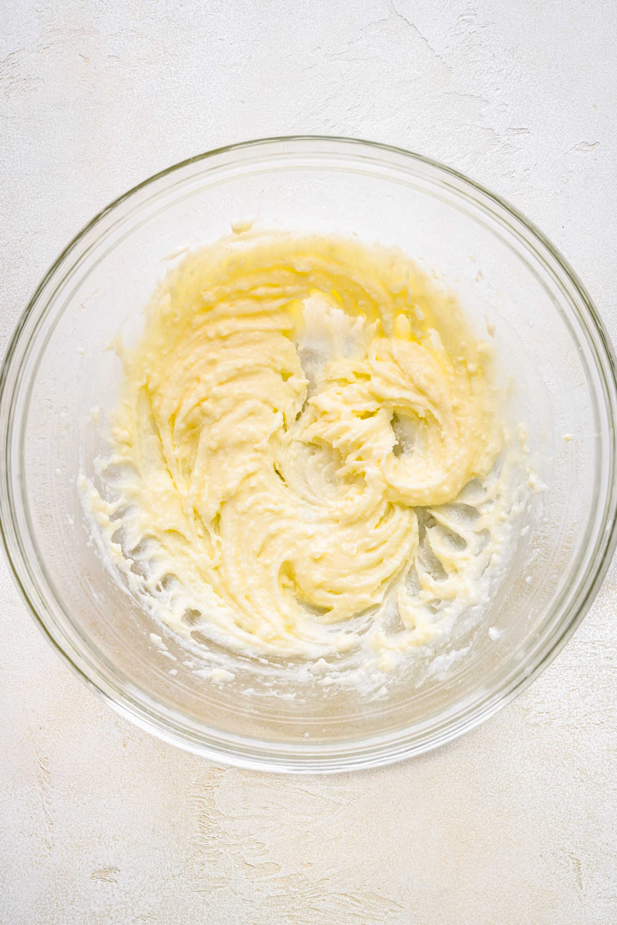 Creamed butter, sugar, and yogurt in a glass mixing bowl. 