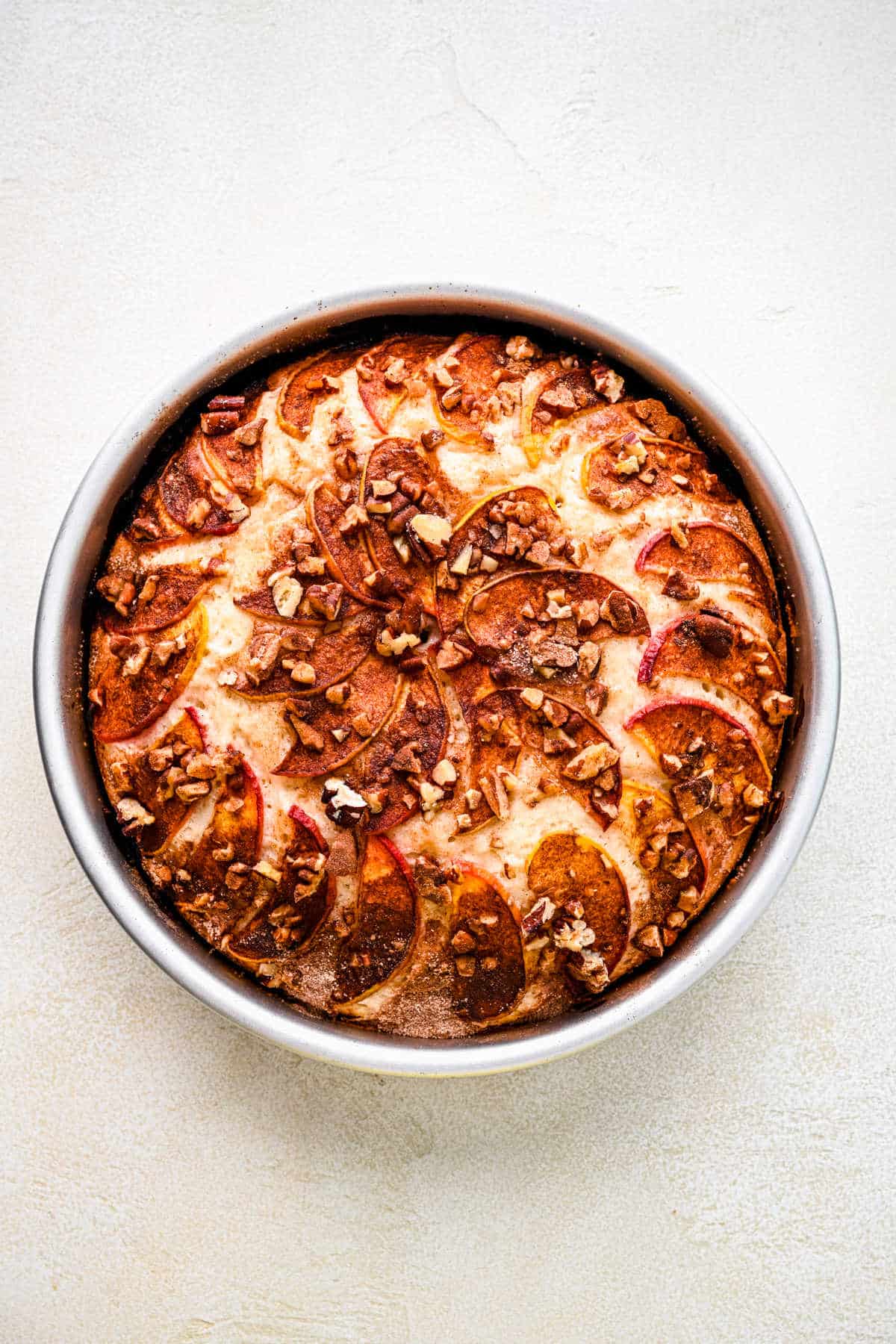 A baked peach cake in a round cake pan.