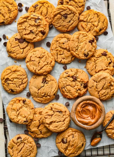 A tray of peanut butter chocolate chip cookies with a dish of peanut butter on it.