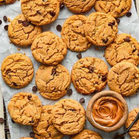 A tray of peanut butter chocolate chip cookies with a dish of peanut butter on it.