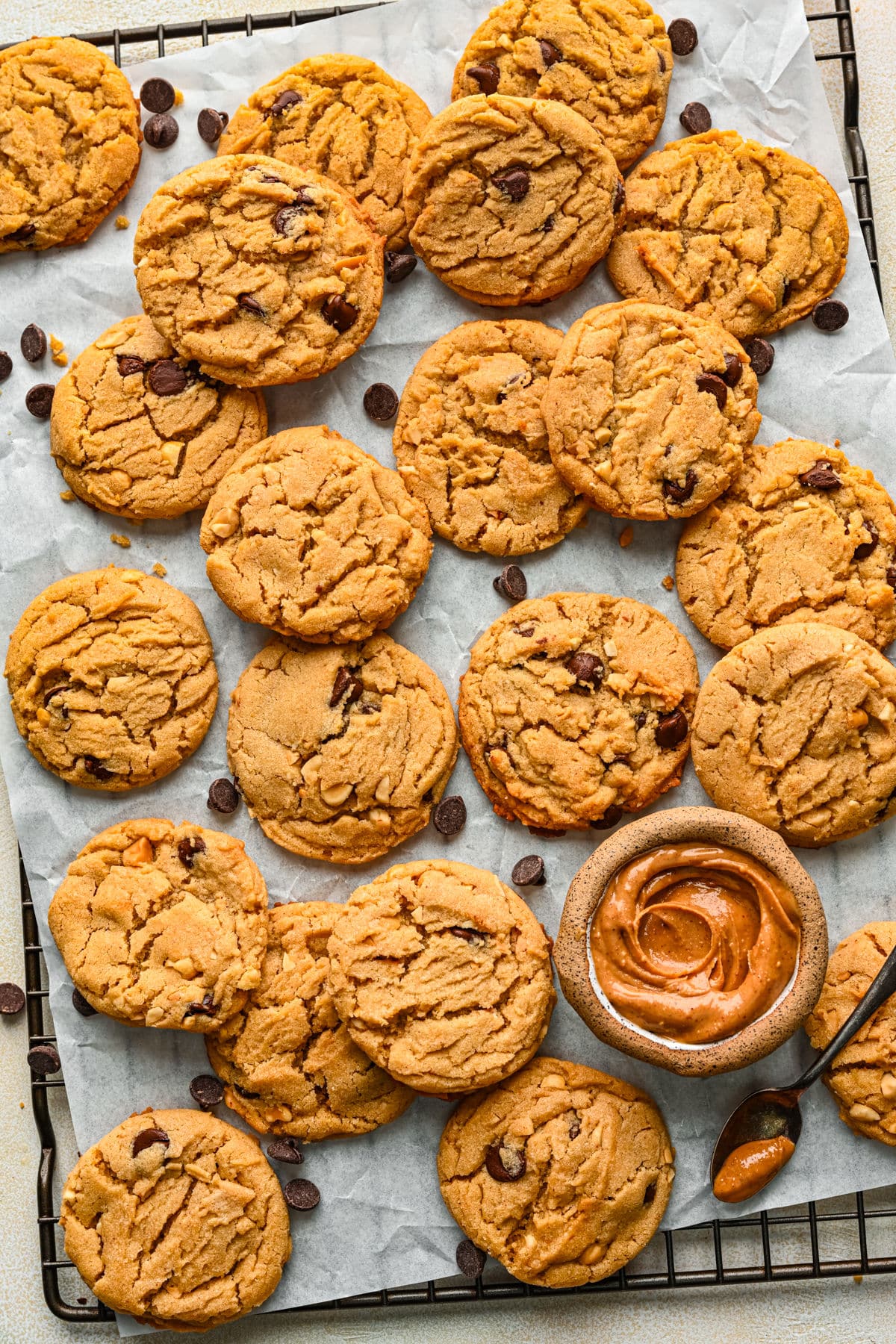 A tray of peanut butter chocolate chip cookies with a dish of peanut butter on it. 